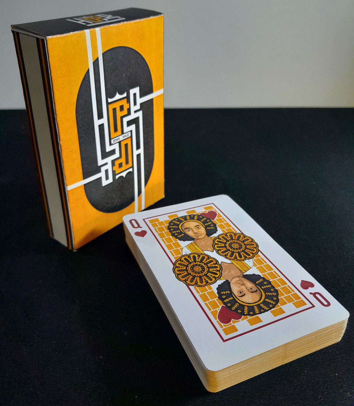 The yellow-and-black Zewd Historical Deck tuck case beside the pack, topped by the Queen of Hearts.